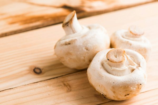 Fresh white mushrooms on a wooden table, showcasing natural textures and earthy tones.